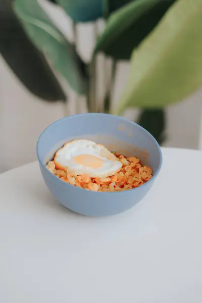 Tahta bir masada beyaz bir tabakla bir kase kızarmış yumurta.