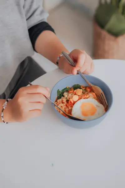 Asyalı kadın kızarmış yumurta ve sebzeli pirinç eriştesi yiyor.