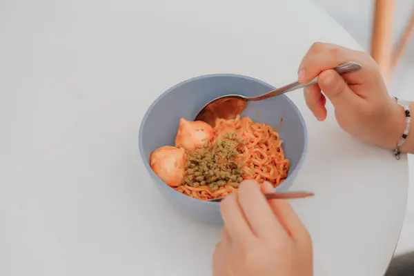 Asyalı kadınlar ellerinde bir kase erişte ve çubuk tutuyorlar.