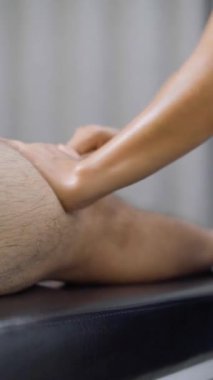 Manos femeninas masajeando una pierna masmanina durante una sesde fisioterapia