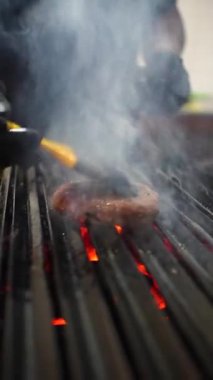 Hamburgeri ateşe vermek için pişirme aletiyle yağlanıyor.