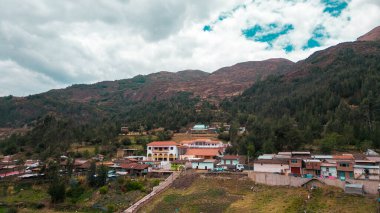 Peru 'nun dağlık kesimlerinde ağaçlarla dolu kayalık bir dağın eteğinde küçük bir köy.