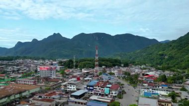 Tingo Mara, Peru - 20 Mart 2024: Güneşli bir yaz gününde Tingo Mara şehrini gösteren bir dron tarafından çekilen çarpıcı hava görüntüsü. Görüntüler ufuktaki yemyeşil dağlarla çevrili kentsel manzarayı vurguluyor..