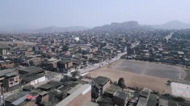 İHA videosu, güneşli bulutsuz bir günde, zayıf inşa edilmiş evleri ve ortasında tozlu bir futbol sahası olan Güney Amerika şehrinin fakir bir bölgesini gösteriyor.
