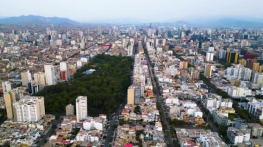 Güneşli bir yaz öğleden sonrasında, binalarla dolu Güney Amerika şehri Lima 'nın göbeğinde canlı yeşil bir park.