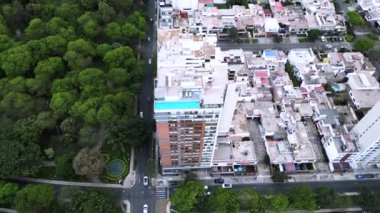 Yoğun bir caddenin köşesinde, yayalar, araçlar ve ağaçlarla dolu büyük bir parkı olan modern bir minimalist bina.