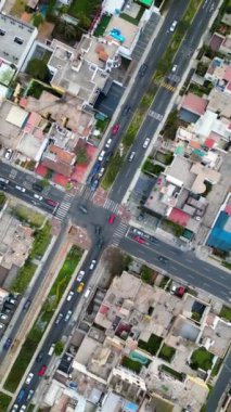 Ortasında ağaçlar ve bulutlu bir öğleden sonra hareket eden arabaların kesiştiği bir cadde manzarası.