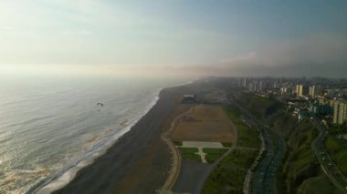 Deniz manzaralı güneşli bir yaz gününde Pasifik kıyısında güçlü bir yamaç paraşütü uçuşu.