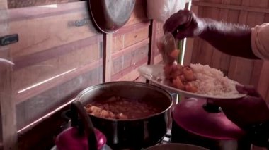 Küçük, mütevazı bir lokantada carapulcra servis eden adam.