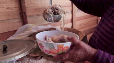 Mütevazi bir ortamda tavuk çorbası servis eden yaşlı bir kadın.