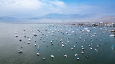 Güneşli bir Ocak gününde sakin sularda süzülen balıkçı tekneleri ve özel yatlarıyla huzurlu Peru Denizi.