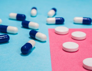 Mavi ve beyaz haplar açık mavi ve kırmızı arka plana saçılmış.