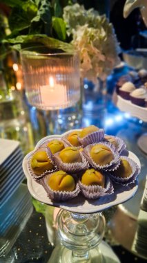 Lezzetli şeftali şekilli badem ezmesi ve arkasında bir mum..