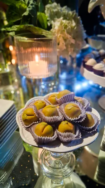 Lezzetli şeftali şekilli badem ezmesi ve arkasında bir mum..