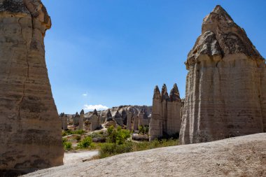 Derin mavi gökyüzü ve aile, içinde hâlâ mağara evleri olan Tuff 'tan yapılmış mantar şekilli kayalarda yürüyor. Aşk Vadisi 'ndeki Kapadokya seyahatinin yaz havası