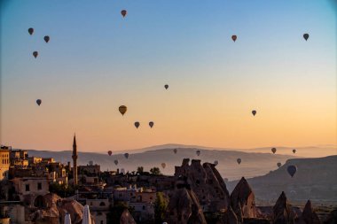 A stunning view of a picturesque valley with majestic mountains rising in the background, creating a breathtaking natural landscape, hot air balloons at dawn against the backdrop of volcanic tufa clipart