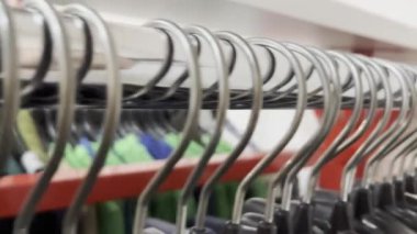 Bir perakende satış ortamında giysi sergilenmeye hazır metal askıların yakın plan görüntüsü.