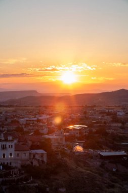 Uchisar şehrinin üzerinde gün batımı, kalenin manzarası, batan güneşin güzel ışıkları eski güzel evlerin çatılarından yansıyor..