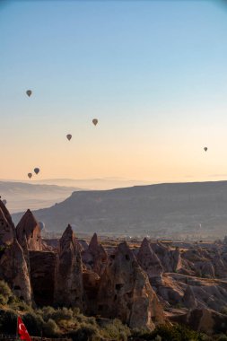 A stunning view of a picturesque valley with majestic mountains rising in the background, creating a breathtaking natural landscape, hot air balloons at dawn against the backdrop of volcanic tufa clipart