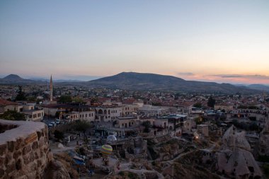 Geniş bir hava manzarası alacakaranlıkta hareketli bir şehir yakalıyor ve çarpıcı dağlar fevkalade arka planda belirgin bir şekilde görülüyor.
