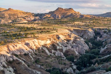 Kapadokyalar inanılmaz derecede eşsiz jeolojik oluşumlar nefes kesen altın bir günbatımıyla şaşırtıcı bir şekilde aydınlatılır. Volkanik kaya tuff 'unun yarattığı mağara evlerinden vadiye bakınız..