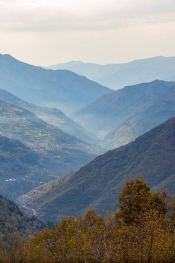 Büyüleyici bir manzara yaratan bulutlu bir günde görkemli dağlarla çevrili geniş bir vadi manzarası.