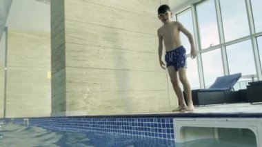 Bir çocuk havuzda rahatça dolaşır, neşeli ruhunu göstererek, şık bir iç mekan ortamında.