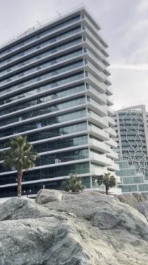 Sahilde cam cepheli, doğal kaya oluşumlarıyla çerçevelenmiş çağdaş bir apartman..