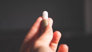 A hand holding white pill medicine minimalist close up photo clipart