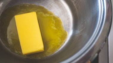 A stick of butter melting in a pot cooking close up photo clipart