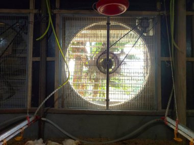 Büyük bir vantilatör ya da üfleyici koruyucu ızgaralı bir bina duvarına monte edilmiş. Bu vantilatör havalandırma ve soğutma işlevleri, büyük boyutu ve dış konumundan dolayı dikkat çekiyor..