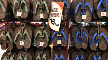 Pinrang-Makassar Endonezya, 28 Ekim 2024: Bir mağazada sergilenen yeşil ve mavi kayışlı siyah parmak arası terlikler. 