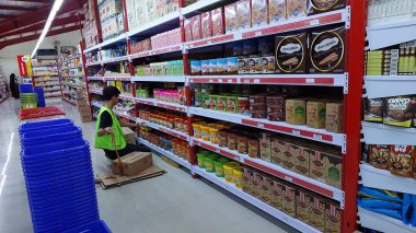 Bir süpermarket çalışanı bir rafta malları düzenliyor.
