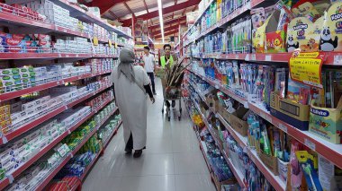 Süpermarket koridorunda, bir ev hanımı ve bir erkek çalışan malları satıyorlar.