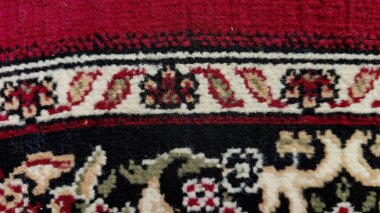 Simetrik geometrik ve çiçek motifli dua halısı. Baskın renkler kırmızı, siyah, krem ve yeşildir. Şablon kalın çizgiler, çiçekli detaylar ve klasik süslemelerden oluşur..