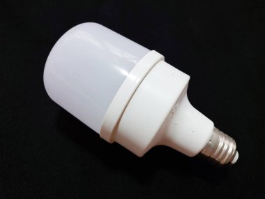 A white LED lamp, short cylindrical in shape with an opaque cover, is placed on a black cloth surface as a background.