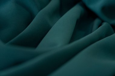 Bir desenli yeşil kumaş parçası. Kumaş katlanmış ve parlak bir görünüme sahip. Kumaş sentetik bir malzemeden yapılmıştır. Sancak, arkaplan veya 3B haritalama dokusu için arka plan