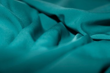 Bir desenli yeşil kumaş parçası. Kumaş katlanmış ve parlak bir görünüme sahip. Kumaş sentetik bir materyalden yapılmıştır. Sancak, arkaplan veya 3D haritalama için doku için arka plan