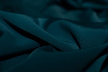 Bir desenli yeşil kumaş parçası. Kumaş katlanmış ve parlak bir görünüme sahip. Kumaş sentetik bir materyalden yapılmıştır. Sancak, arkaplan veya 3D haritalama için doku için arka plan