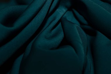 Bir desenli yeşil kumaş parçası. Kumaş katlanmış ve parlak bir görünüme sahip. Kumaş sentetik bir materyalden yapılmıştır. Sancak, arkaplan veya 3D haritalama için doku için arka plan