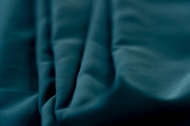 Bir desenli yeşil kumaş parçası. Kumaş katlanmış ve parlak bir görünüme sahip. Kumaş sentetik bir materyalden yapılmıştır. Sancak, arkaplan veya 3D haritalama için doku için arka plan