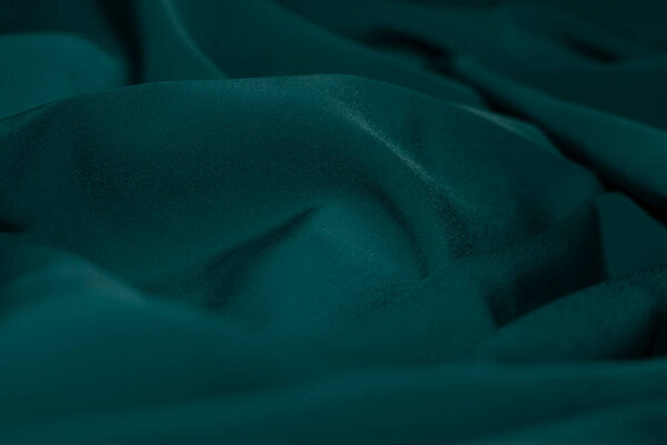 Кусок зелёной ткани с узором. Ткань сложена и имеет блестящий внешний вид. Фон для баннера, подложки или текстуры для трехмерного отображения.