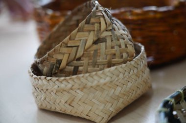 Bambu dokuması sepet şeklinde, karmaşık desenlerle örülmüş, geleneksel el sanatları ve basit ve mütevazı tasarımları vurgulayan doğal bir dokusu vardır..