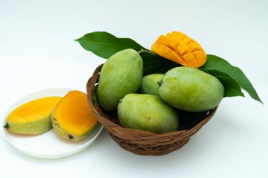 green mangoes and mango slices in a basket on a white background