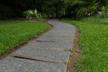 Yol taş levhalarla döşenmiş. Doğanın ortasında, ağaçlar. Parktaki patika