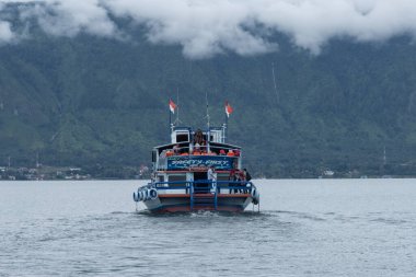Kuzey Sumatra, Toba Gölü 'nde turist taşıyan küçük bir feribot denize açılıyor.
