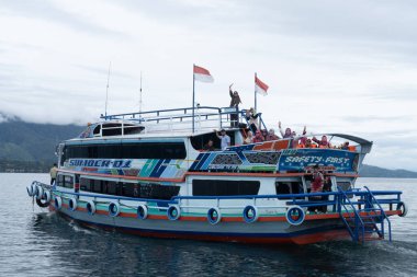 Kuzey Sumatra, Toba Gölü 'nde turist taşıyan küçük bir feribot denize açılıyor.