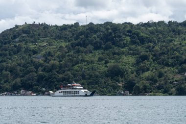 Kuzey Sumatra, Toba Gölü 'nde turist taşıyan küçük bir feribot denize açılıyor.