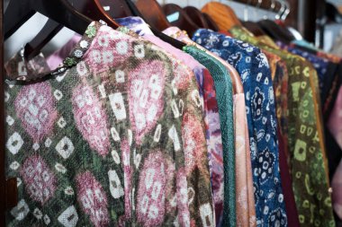 Batik, dokuma ve Endonezya 'nın Palembang kentindeki bir mağazadaki askılarda bulunan ekoprint de dahil olmak üzere çeşitli geleneksel motiflere sahip kadın giysileri.