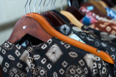 Batik, dokuma ve Endonezya 'nın Palembang kentindeki bir mağazadaki askılarda bulunan ekoprint de dahil olmak üzere çeşitli geleneksel motiflere sahip kadın giysileri.